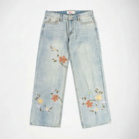 Light wash blue denim Bubblegum jeans with embroidered floral patterns in orange, yellow, and green on both legs, shown flat against a white background.