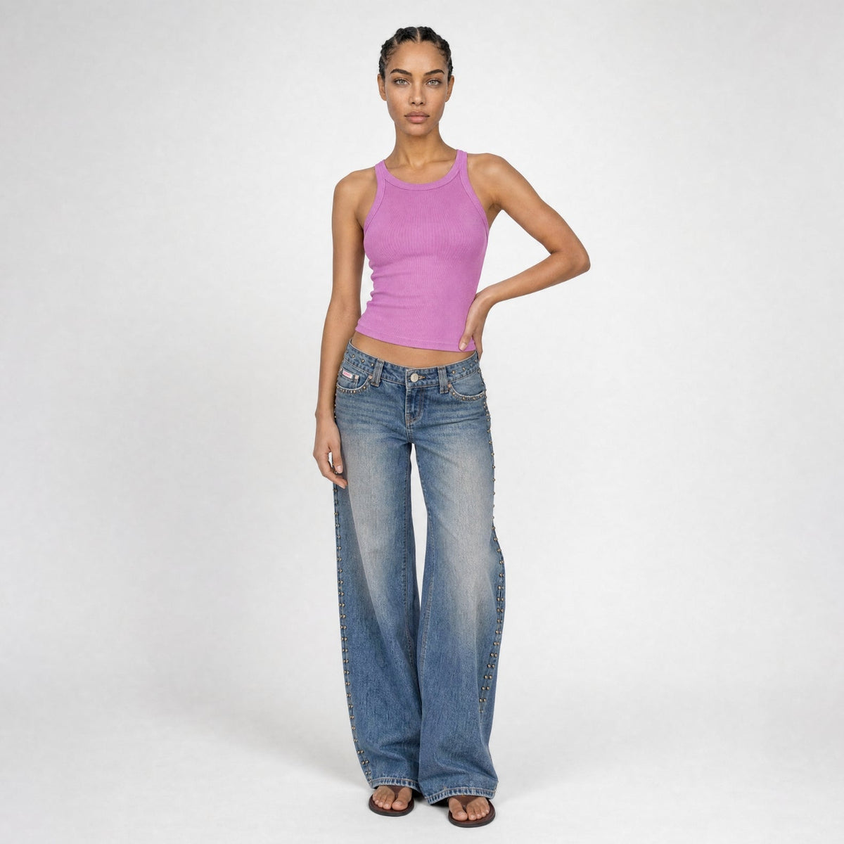 A model wearing a purple tank top with mid indigo denim wash Bubblegum jeans posing in front of a white background.