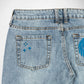Close-up back view of light-wash blue denim Bubblegum jeans showing the waistband, belt loops, and back pockets with blue embroidered and rhinestone details.