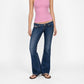 A model wearing a pink tank top and the Jane super low rise flare jeans in mid indigo vintage wash from Bubblegum USA brand, front of a white background.