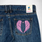 Close-up of the back of dark blue denim Bubblegum jeans showing a pink embroidered angel wings design on the back pocket, with a visible Bubblegum USA brand patch at the waistband.