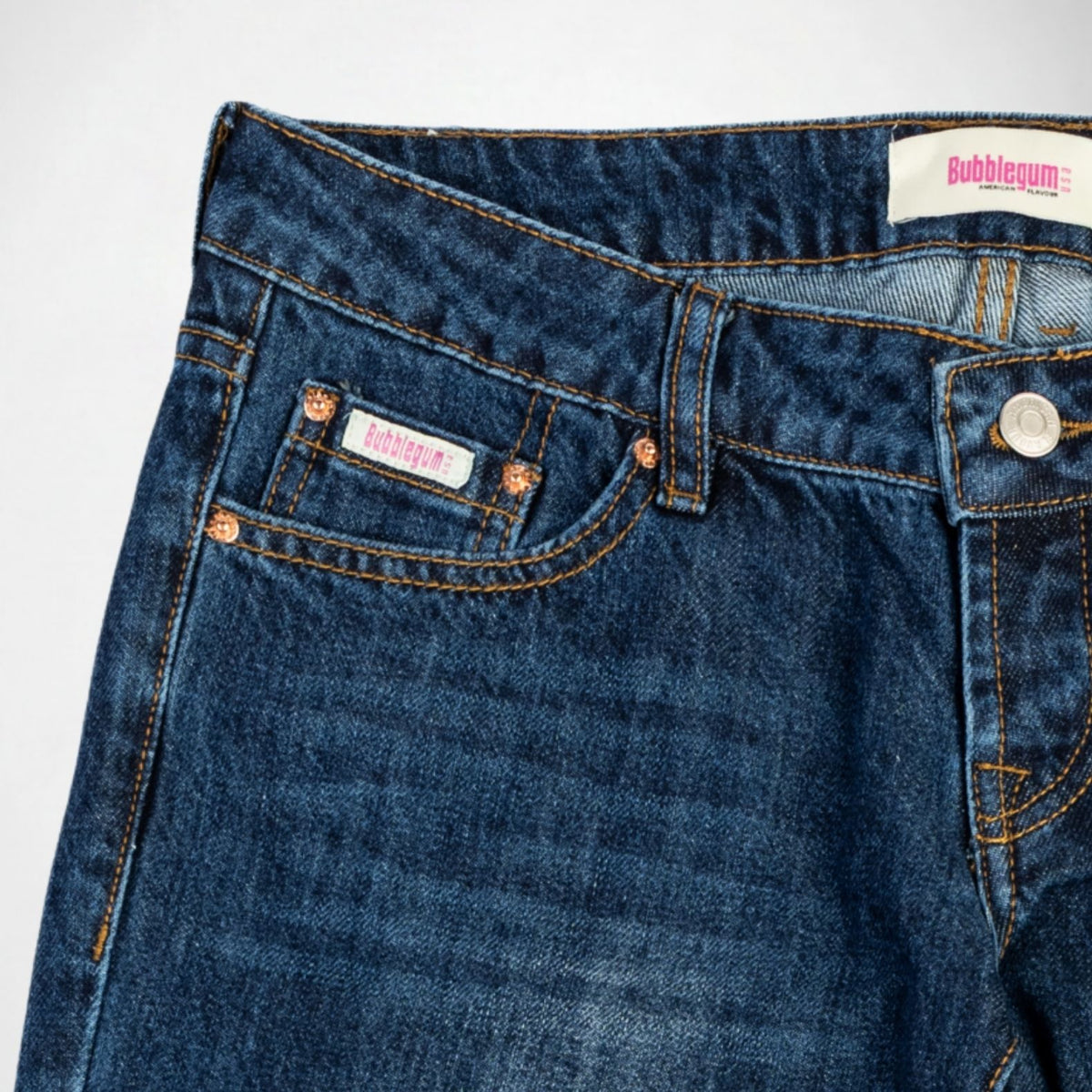 Close-up of dark blue denim Bubblegum jeans showing the waistband, front pocket, rivets, and a visible Bubblegu. USA brand label.