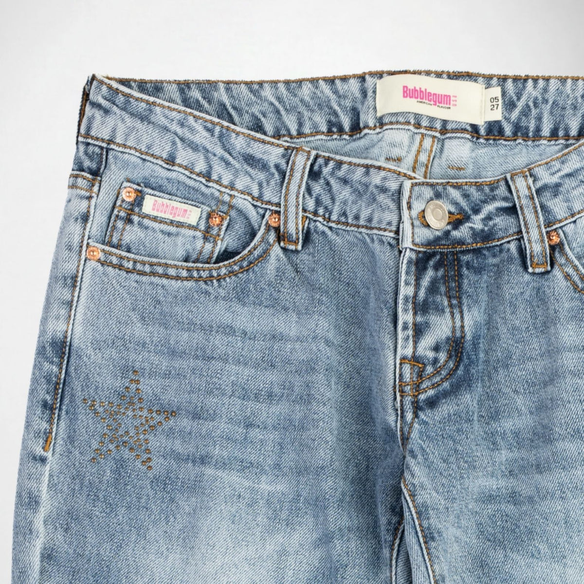 Close-up of a pair of light blue denim Bubblegum jeans showing the front waistband, button closure, pocket details, and a star embellishment on the upper left leg.