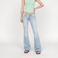 A model wearing the Rose super low rise, flare leg in vintage light-wash blue Bubblegum jeans, a mint green ribbed tank top, and brown sandals, standing against a plain white studio background.