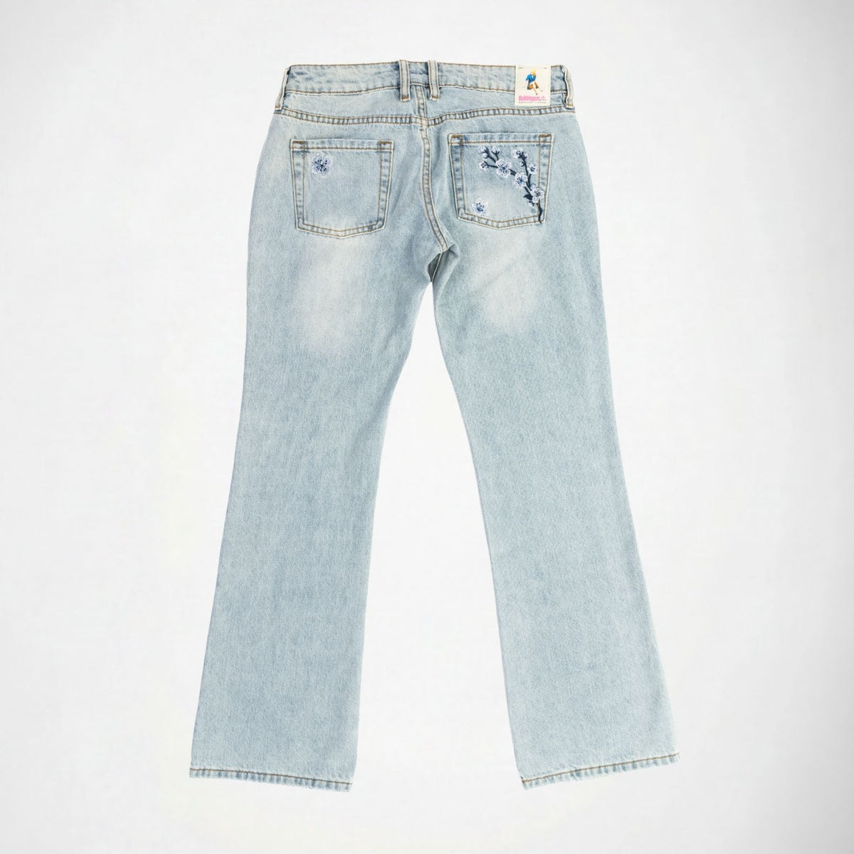 Light wash blue denim Bubblegum jeans shown from the back, featuring indigo and white cherry blossom flower embroidered details on the back pockets and a small colorful 'Bubblegum USA' brand label at the waistband, laid flat against a white background.