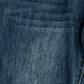 Close-up of dark blue denim fabric with a visible pocket seam and a sliver of orange contrast stitching on the right edge.