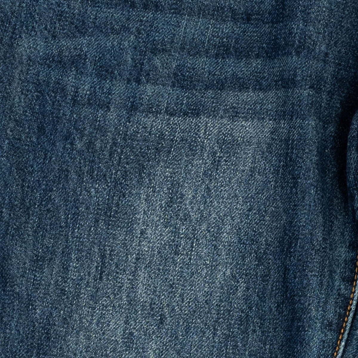 Close-up of dark blue denim fabric with a visible pocket seam and a sliver of orange contrast stitching on the right edge.