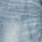 A close-up texture shot of light blue denim fabric with a subtle faded wash and visible diagonal twill weave.