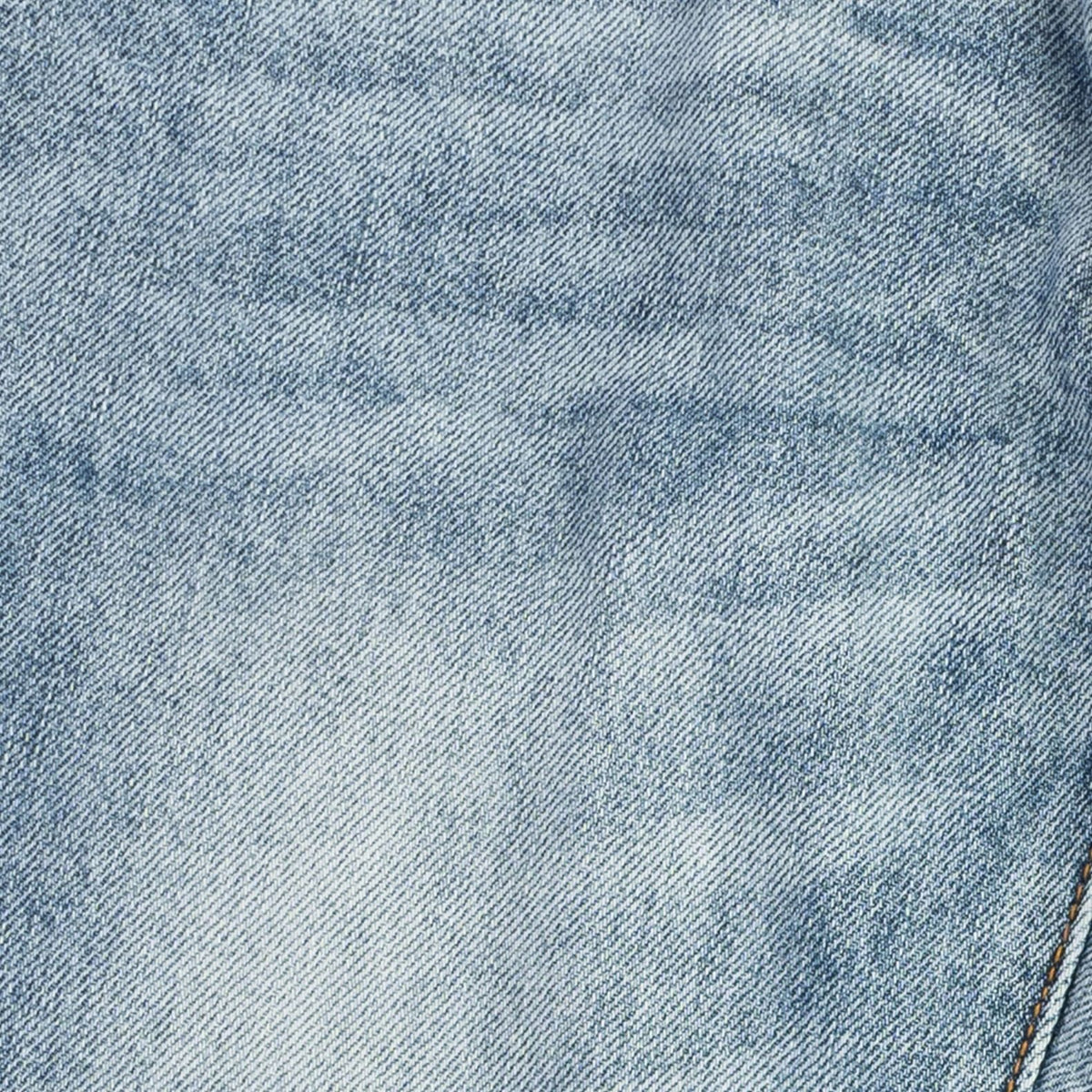 A close-up texture shot of light blue denim fabric with a subtle faded wash and visible diagonal twill weave.