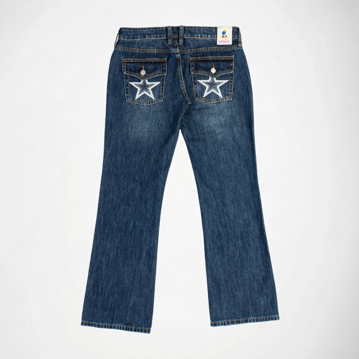 Back view of a pair of blue denim Bubbldgum jeans with white embroidered stars with rhinestones on the back pockets, shown flat on a light gray background.