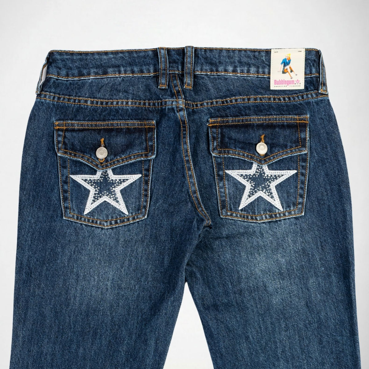 Back view of blue denim Bubblegum jeans with white embroidered stars and rhinestones on both back pockets and a visible 'Bubblegum USA' brand label at the waistband.