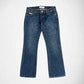 A pair of medium-wash blue denim Bubblegum jeans with the Nola super low rise, flare leg, laid flat against a light gray background.