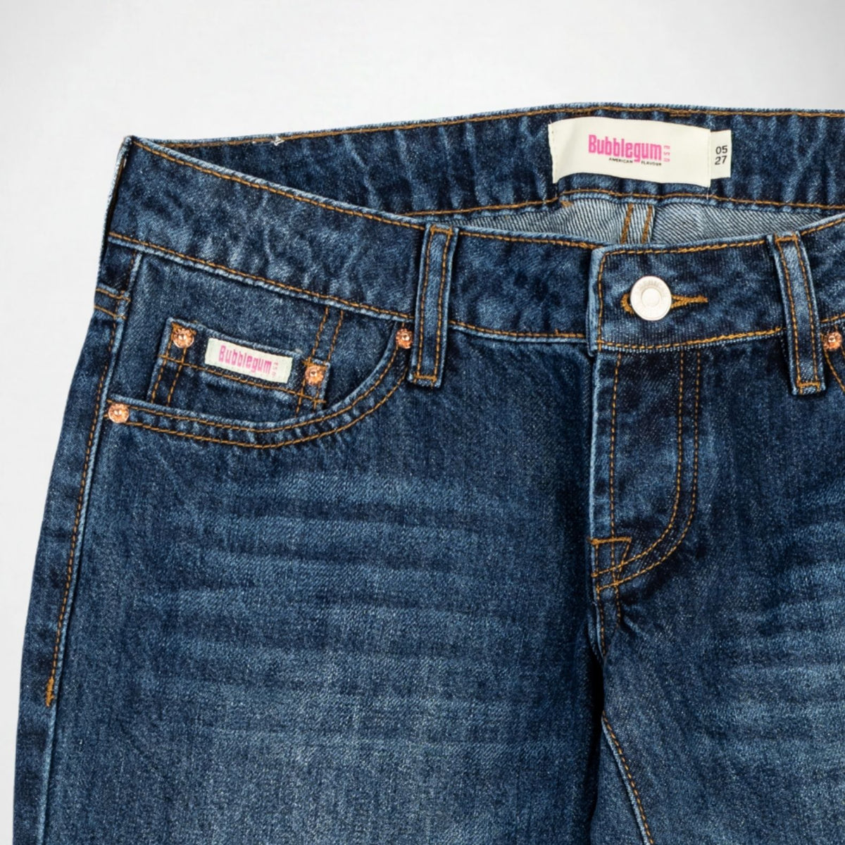 Close-up of a pair of dark blue denim Bubblegum jeans showing the waistband, front button closure, pocket details, and a visible 'Bubblegum USA' brand label.