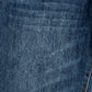 A close-up of dark blue denim fabric with a subtle diagonal twill texture and a small portion of orange contrast stitching visible on the right edge.