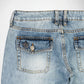 Close-up back view of light-wash blue denim Bubblegum jeans showing the waistband, belt loops, and back pockets with silver stud metallic embellished details.