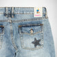 Close-up of the back waistband and pocket area of light-wash blue denim Bubblegum jeans. A square brand patch reading 'Bubblegum USA' is visible at the back waist, and a silver studs embellished star-shaped to the right back pocket.