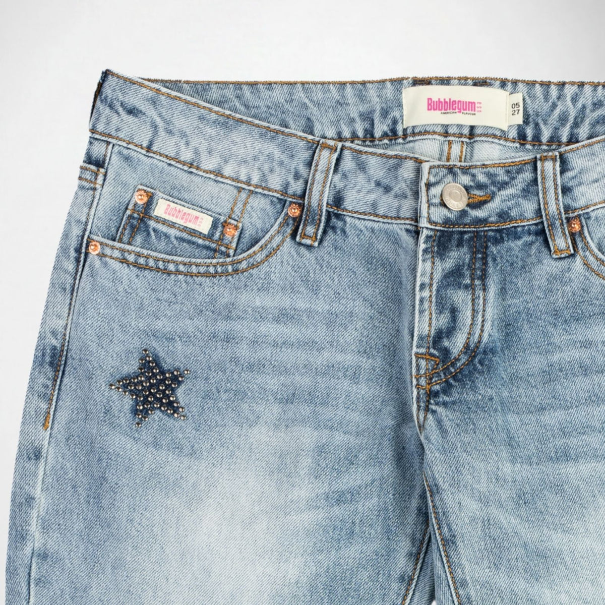 Close-up of a pair of light blue denim Bubblegum jeans with a star-shaped stud embellishment on the front leg panel, featuring a visible Bubblegum USA brand label.