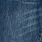 A close-up of dark blue denim fabric with a subtle diagonal twill texture and a small portion of orange-brown stitching visible in the lower right corner.
