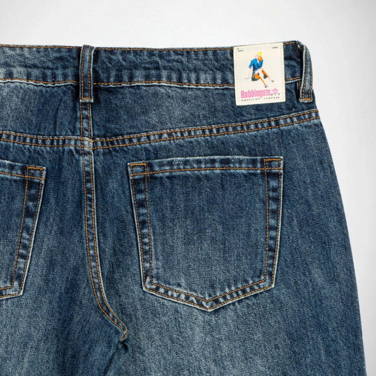 Close-up back view of blue denim Bubblegum jeans showing the waistband, belt loops, back pockets, and a visible Bubblegum USA label.