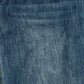 A close-up texture shot of medium-wash blue denim fabric, showing the detailed twill weave and subtle fading.