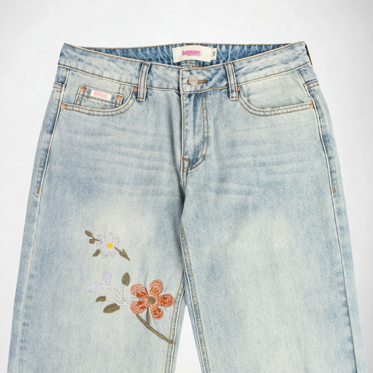 Light-wash blue denim Bubblegum jeans with floral embroidery on the left leg, featuring a white and yellow flower and a coral-orange flower with green leaves, shown against a plain white background.