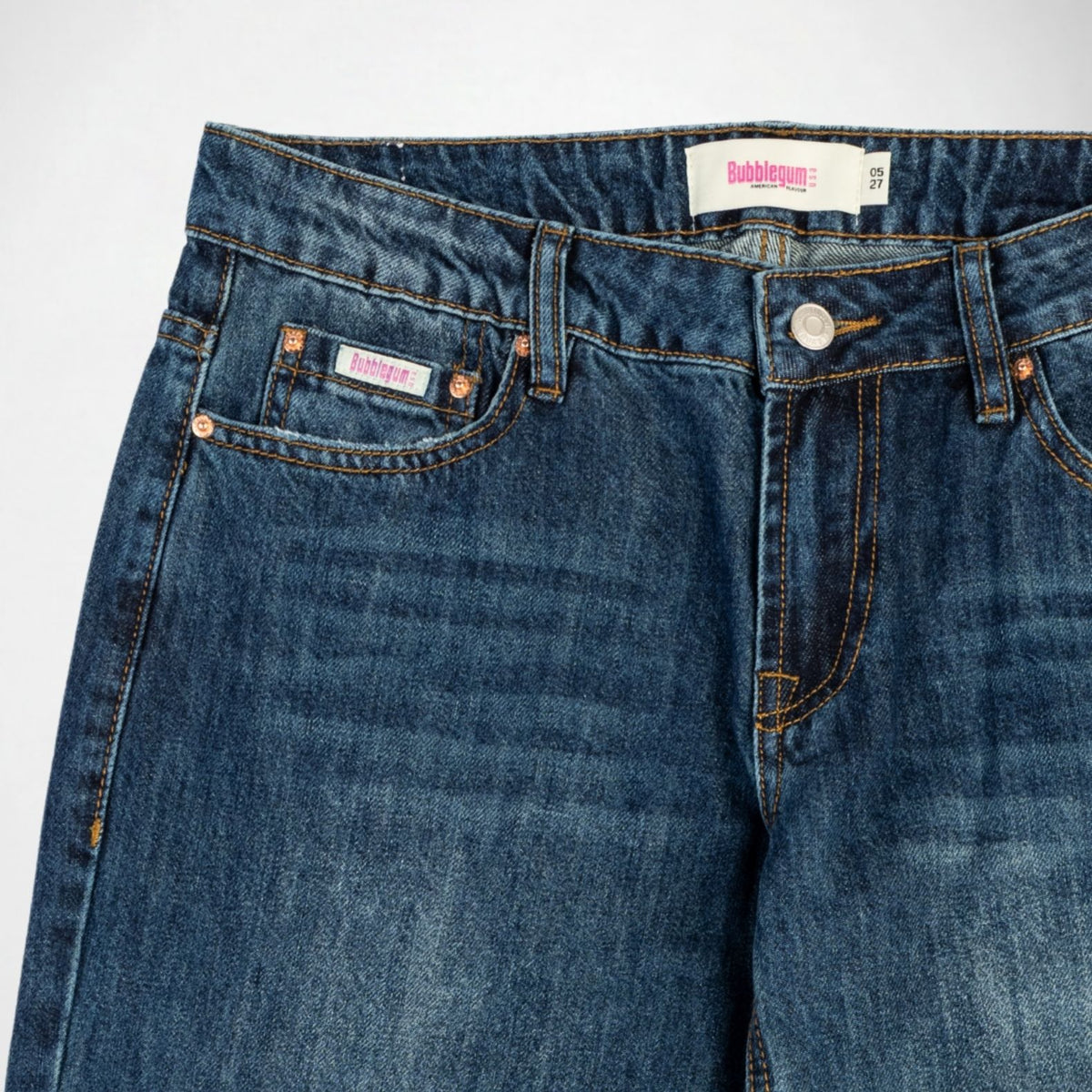 Close-up of a pair of dark blue denim Bubblegum jeans showing the waistband, belt loops, front pockets, rivets, and a visible Bubblegum USA brand label.