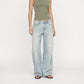 A model wearing the Lisa low baggy wide in mid-rise light-wash, wide-leg Bubblegum denim jeans with a ribbed olive green tank top and black sandals, standing against a plain white studio background.