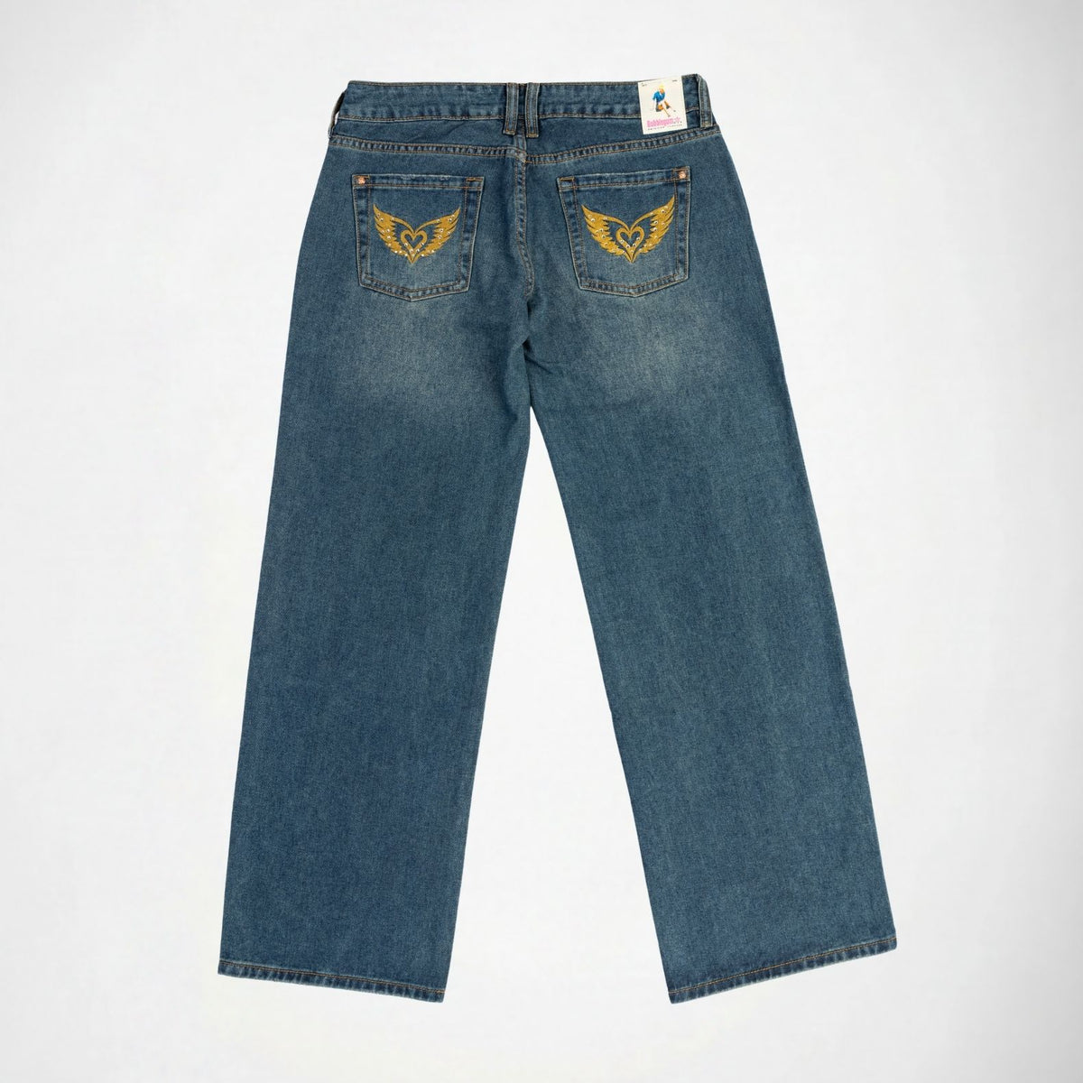 Back view of a pair of blue denim Bubblegum jeans with gold thread embroidered winged heart with rhinestones on both back pockets, displayed flat against a white background.