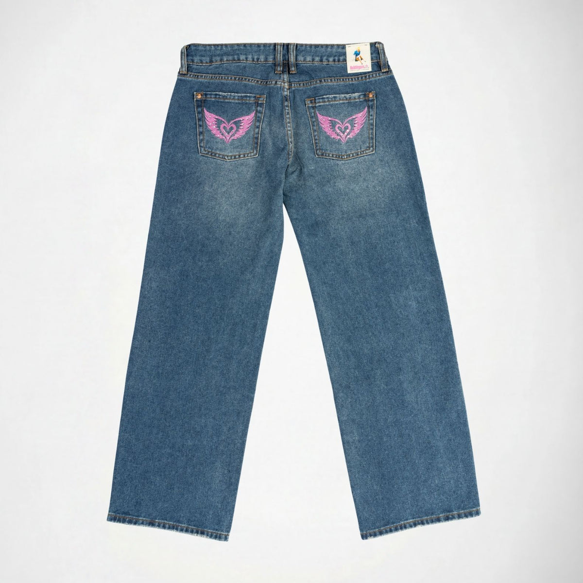 Back view of a pair of blue denim Bubblegum jeans with pink embroidered winged with rhinestones on both back pockets, shown flat against a white background.