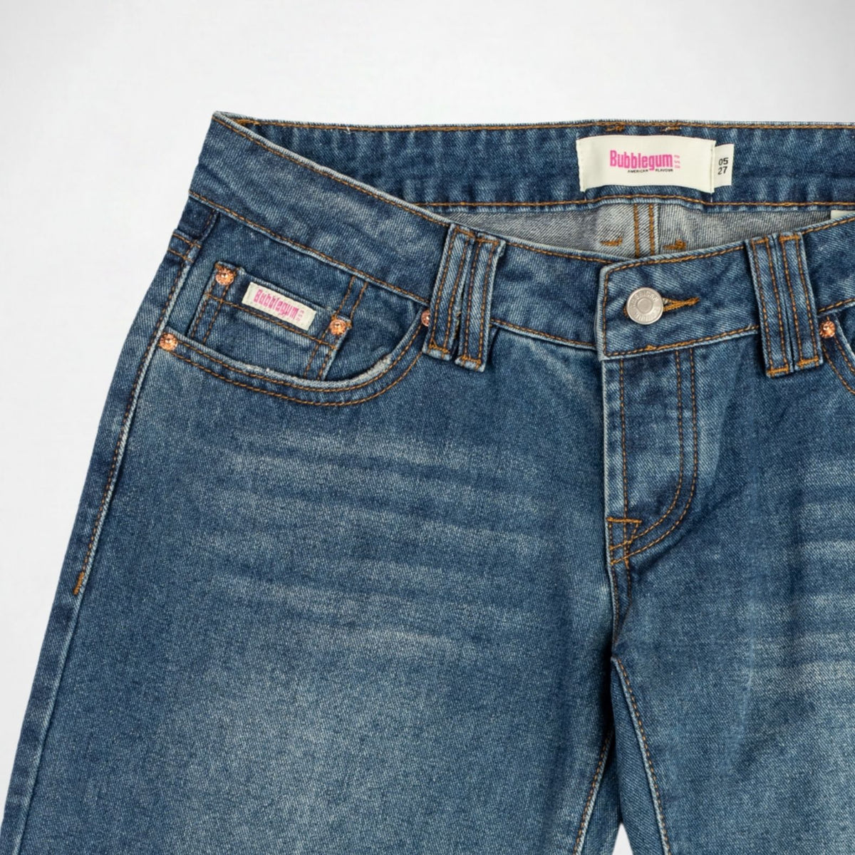 Close-up of a pair of blue denim Bubblegum jeans showing the waistband, front pocket, button, and rivets. The brand label 'Bubblegum USA' is visible on the inner waistband and on the front pocket.