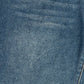 A close-up of blue denim fabric showing the woven texture and a subtle diagonal seam.