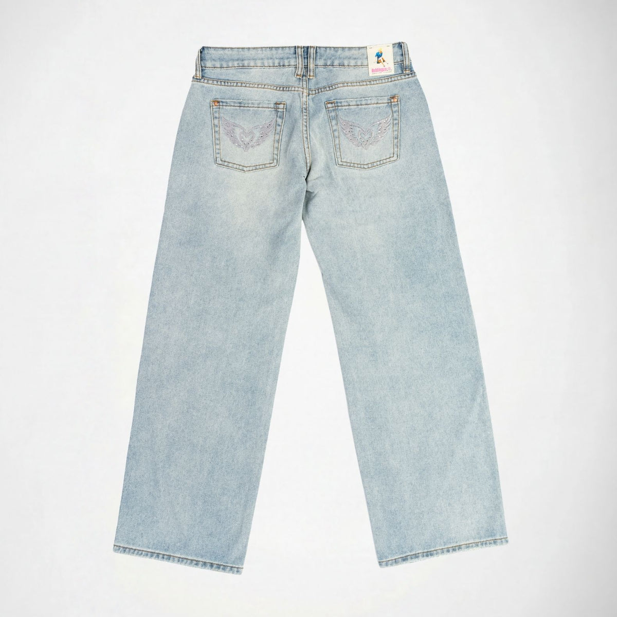 Back view of light-wash blue denim Bubblegum jeans with wings heart embroidered details with rhinestones on the back pockets, laid flat on a white background.