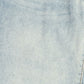 A close-up of light-wash blue denim fabric showing the twill weave texture and subtle fading.