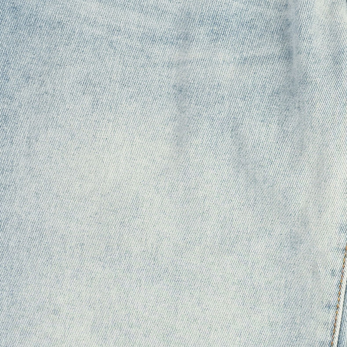 A close-up of light-wash blue denim fabric showing the twill weave texture and subtle fading.