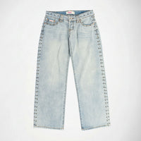 Light wash blue denim Bubblegum jeans with silver metal studs running down the outer seams of both legs, shown flat against a white background.