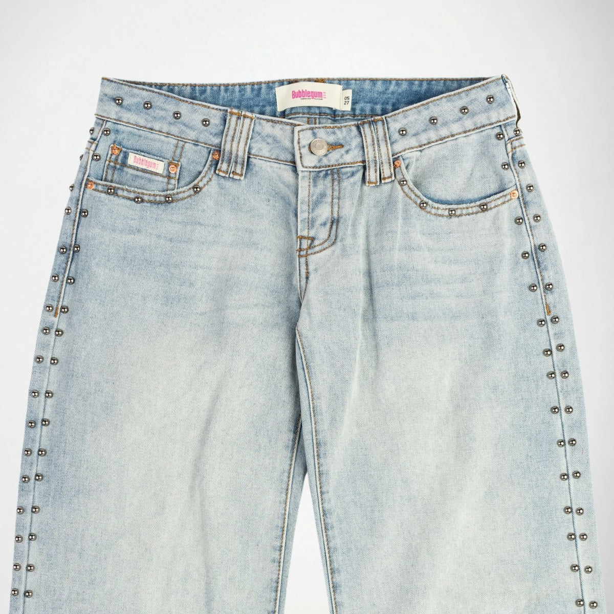 Light wash blue denim Bubblegum jeans with silver metal studs running down the outer seams of the legs, shown against a plain white background.