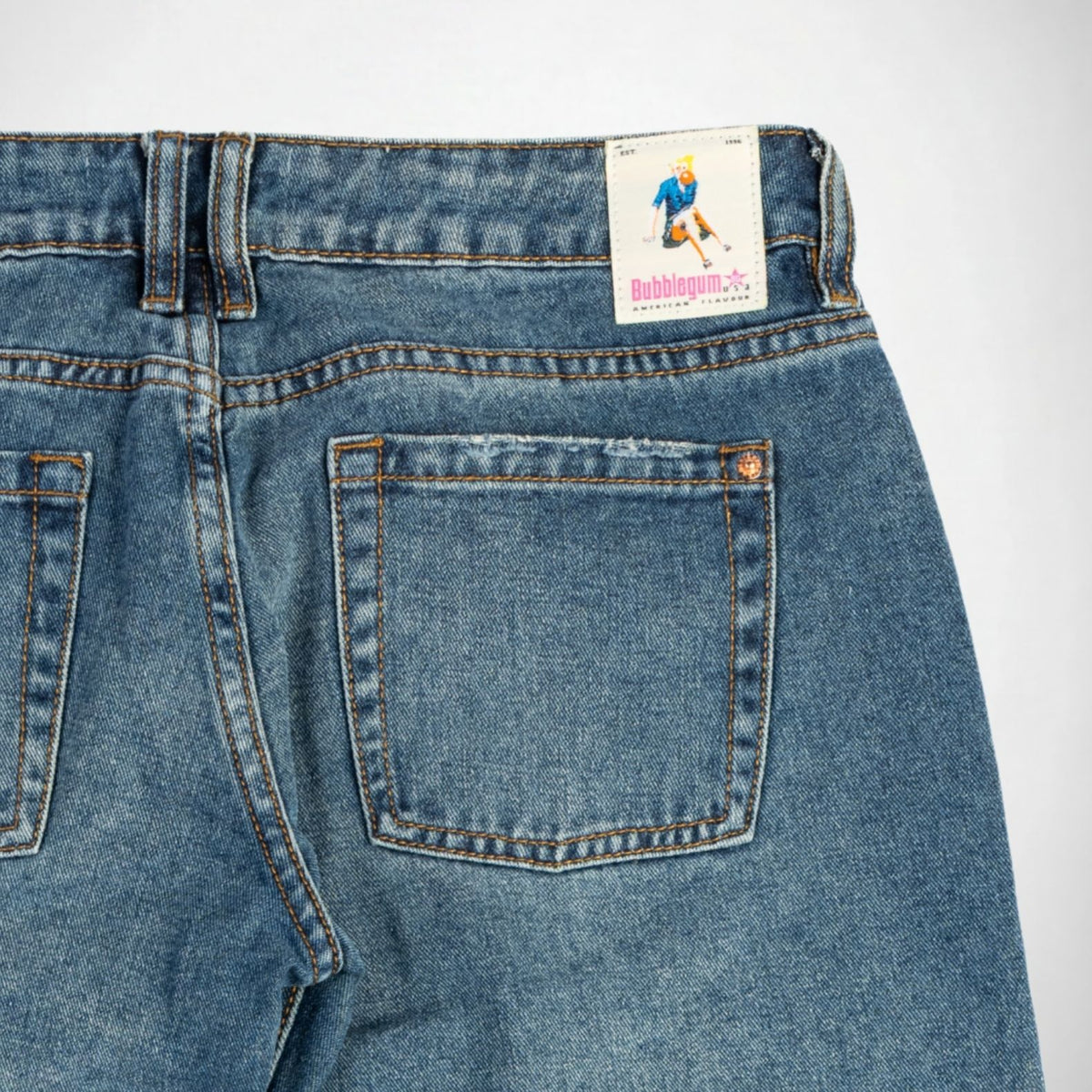 Close-up back view of blue denim Bubblegum jeans showing the waistband, belt loops, back pocket, and a visible Bubblegum brand patch.