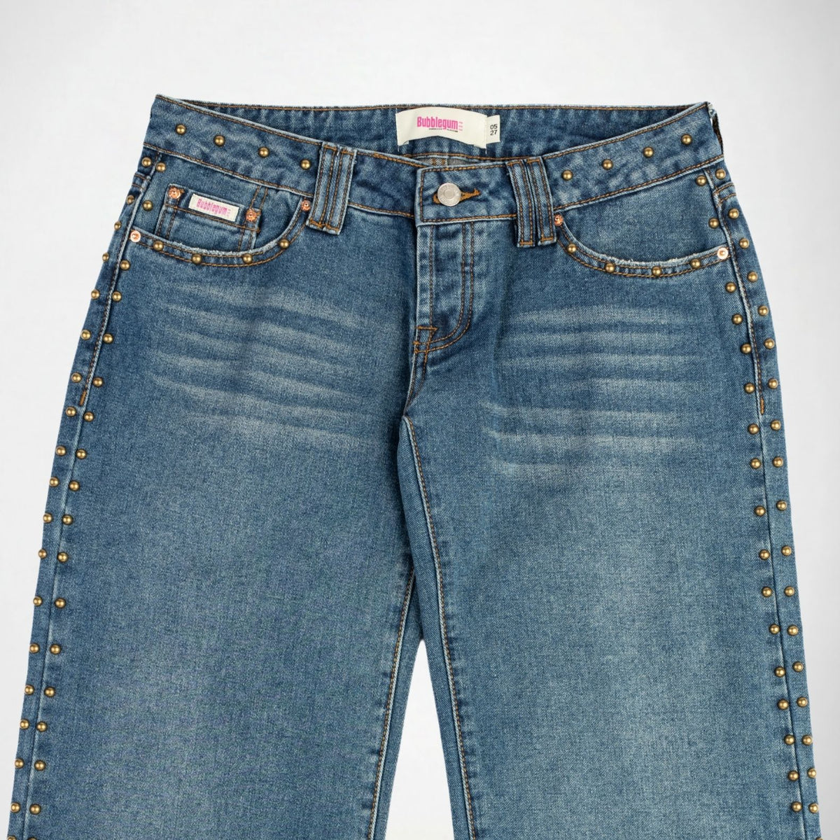 A pair of blue denim Bubblegum jeans with gold-toned metal studs running down the outer seams, shown against a plain white background.