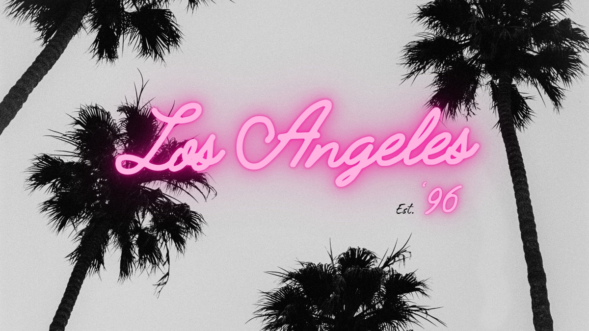 Pink neon-style script text reading 'Los Angeles' with smaller 'Est. 96' text, set against a pale gray background with black palm tree silhouettes. Here since '96. Every fade has a story. Bubblegum USA.
